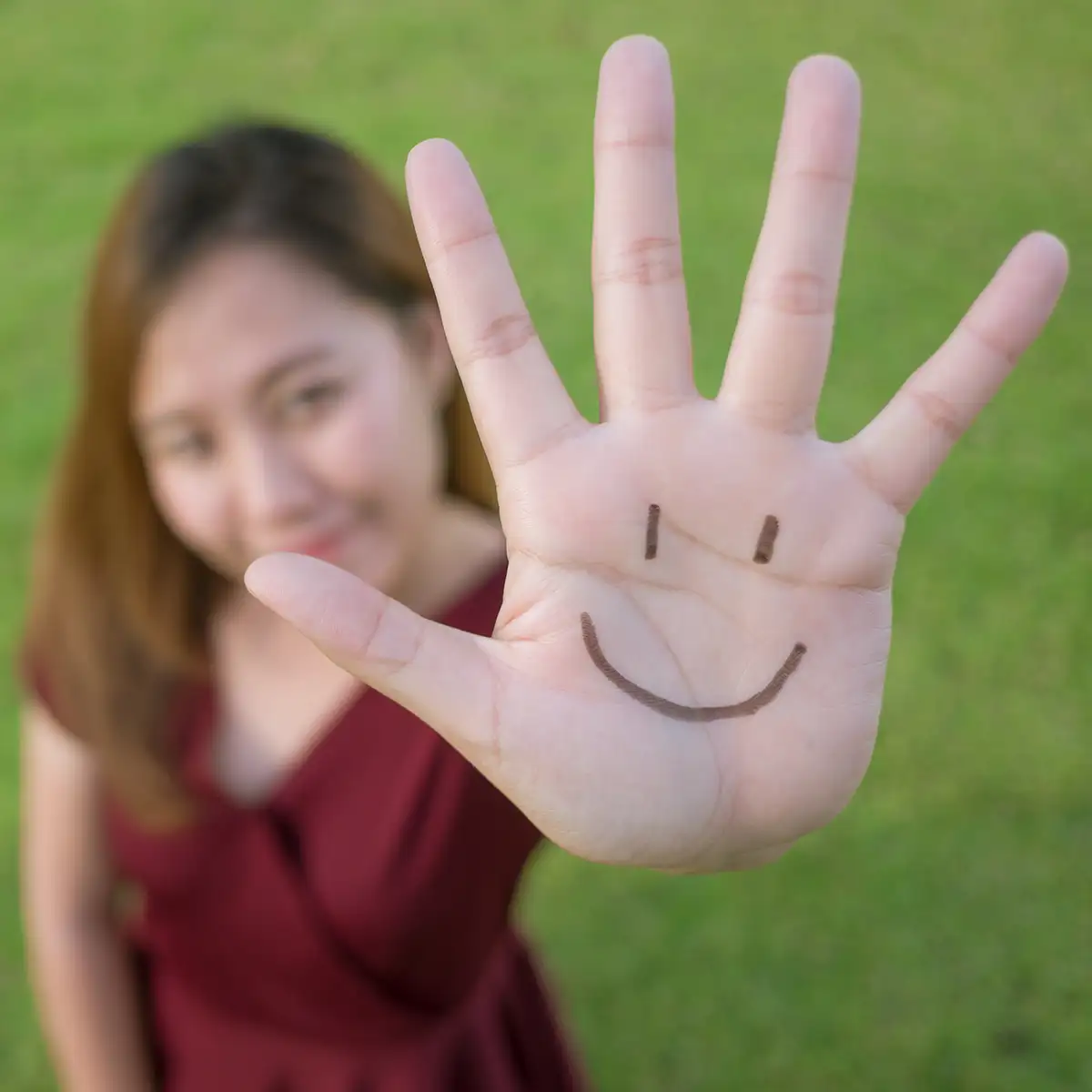 Woman showing hand with a drawn smiley face, representing community support and positivity in Londonderry, New Hampshire.